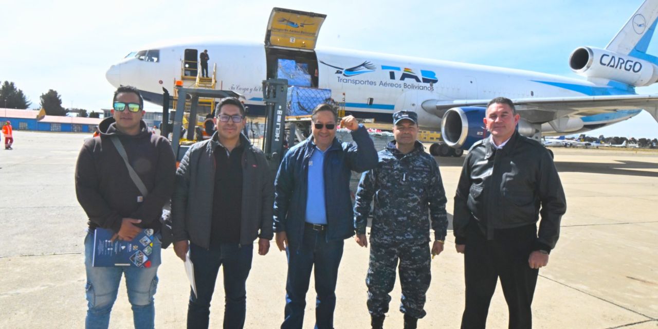 El presidente Luis Arce, junto a otras autoridades, y de fondo uno de los aviones que transportó alimentos.