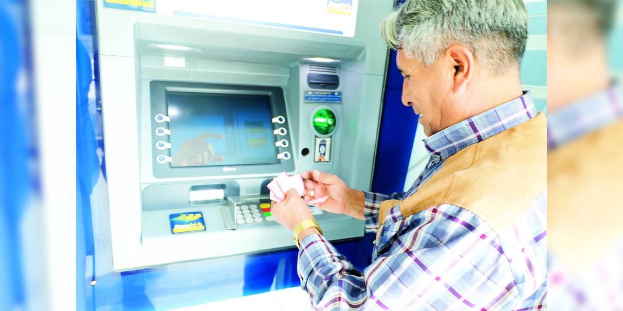 Un jubilado retira su renta de un cajero automático.