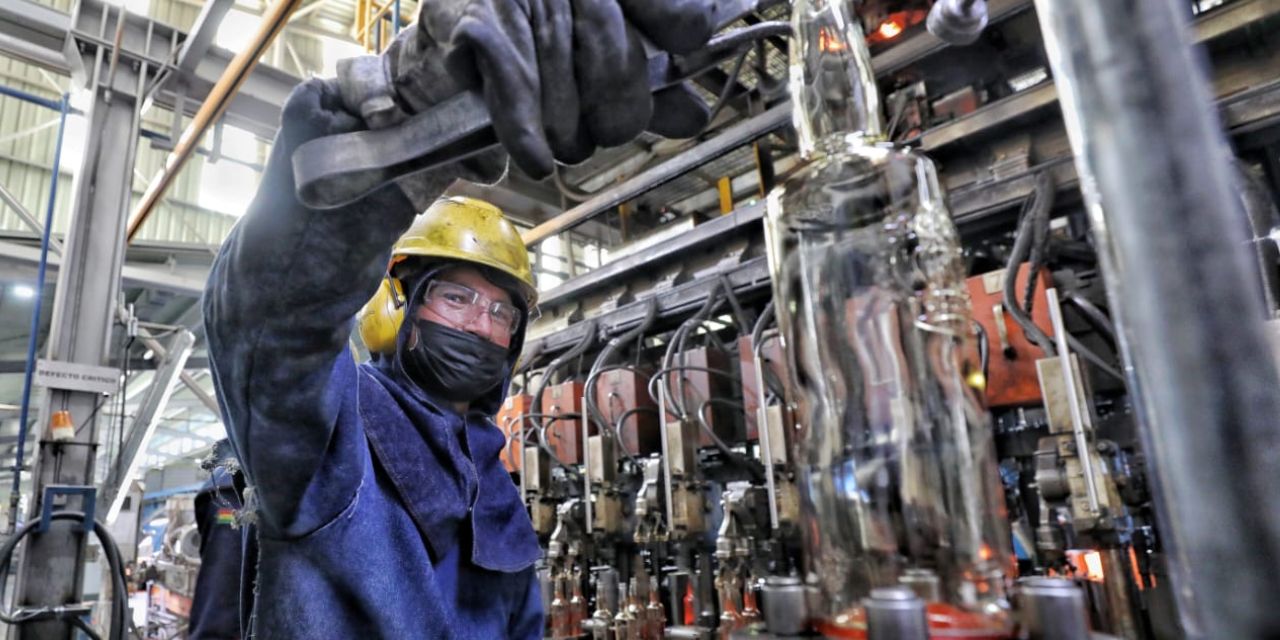 Un operario manipula maquinaria para la elaboración de una botella de vidrio.