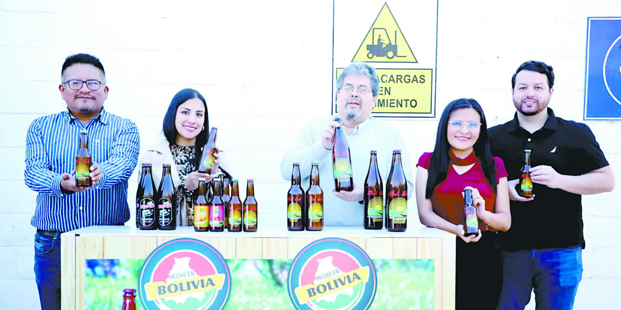 Los representantes de Envibol y de Industrias del Valle, junto a las botellas.