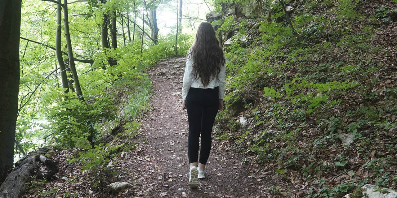 Una mujer camina sola por un sendero.