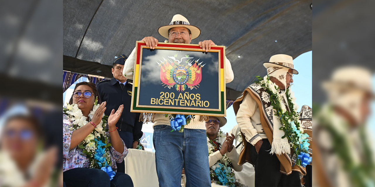 El presidente Luis Arce en un acto en Oruro muestra el presente recibido, un cuadro de Bolivia con alusión al Bicentenario.