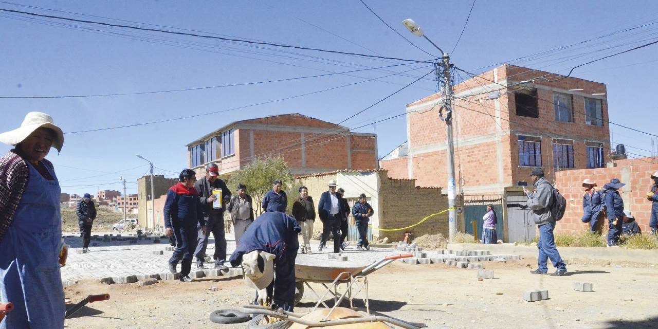 Un grupo de trabajadores, entre ellos mujeres, adoquinan  una vía en El Alto.