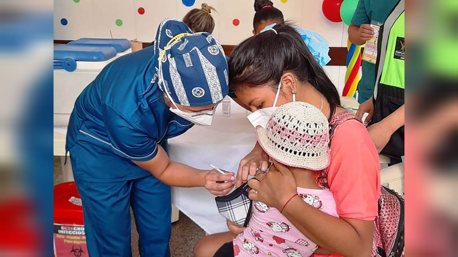 Personal de salud inmuniza a una recién nacida contra la coqueluche.