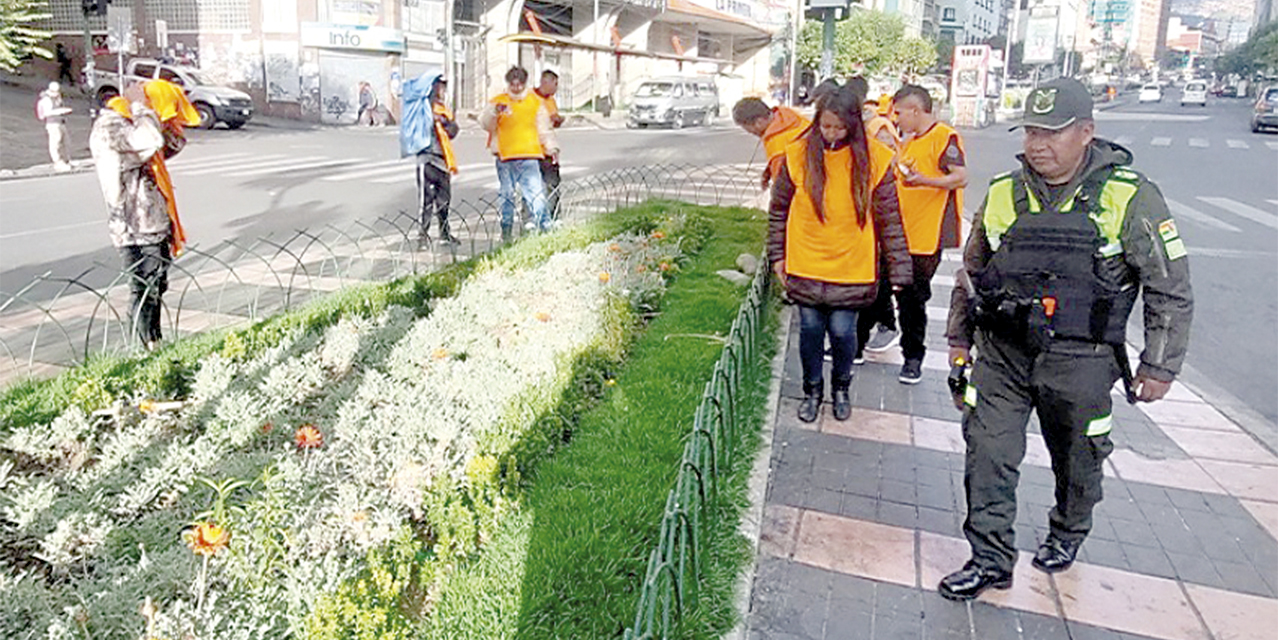 Los infractores en El Prado, con tareas de aseo bajo vigilancia policial.