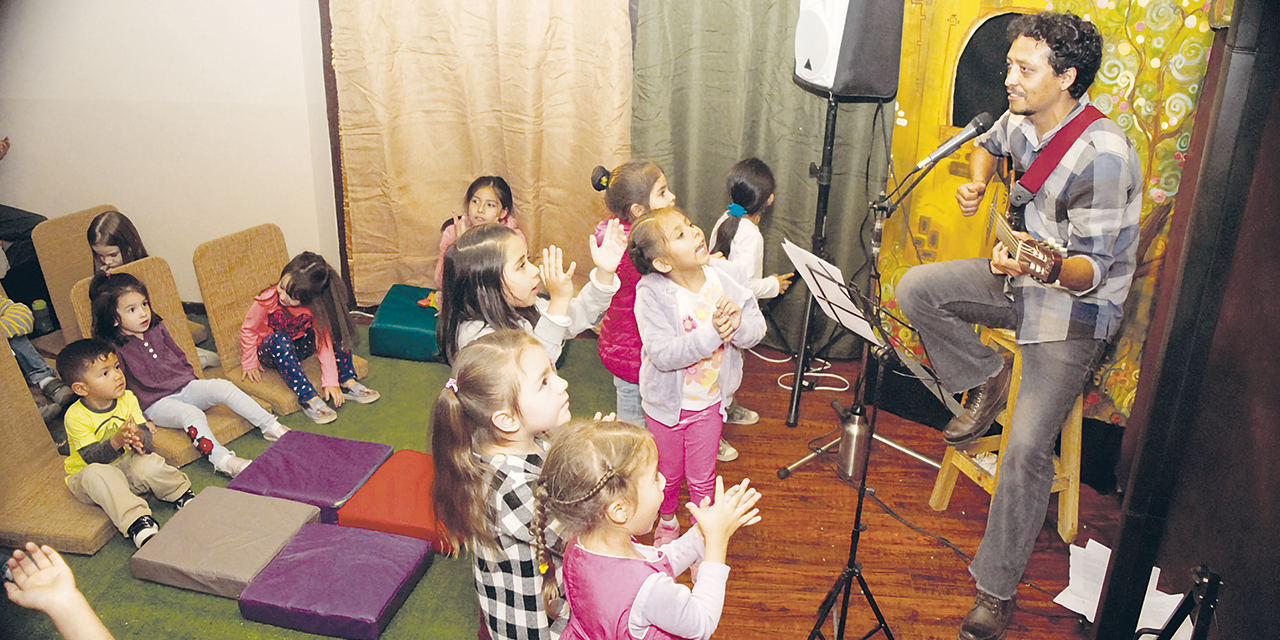 El compositor Marcelo Arias interpreta sus canciones para un grupo de niños.