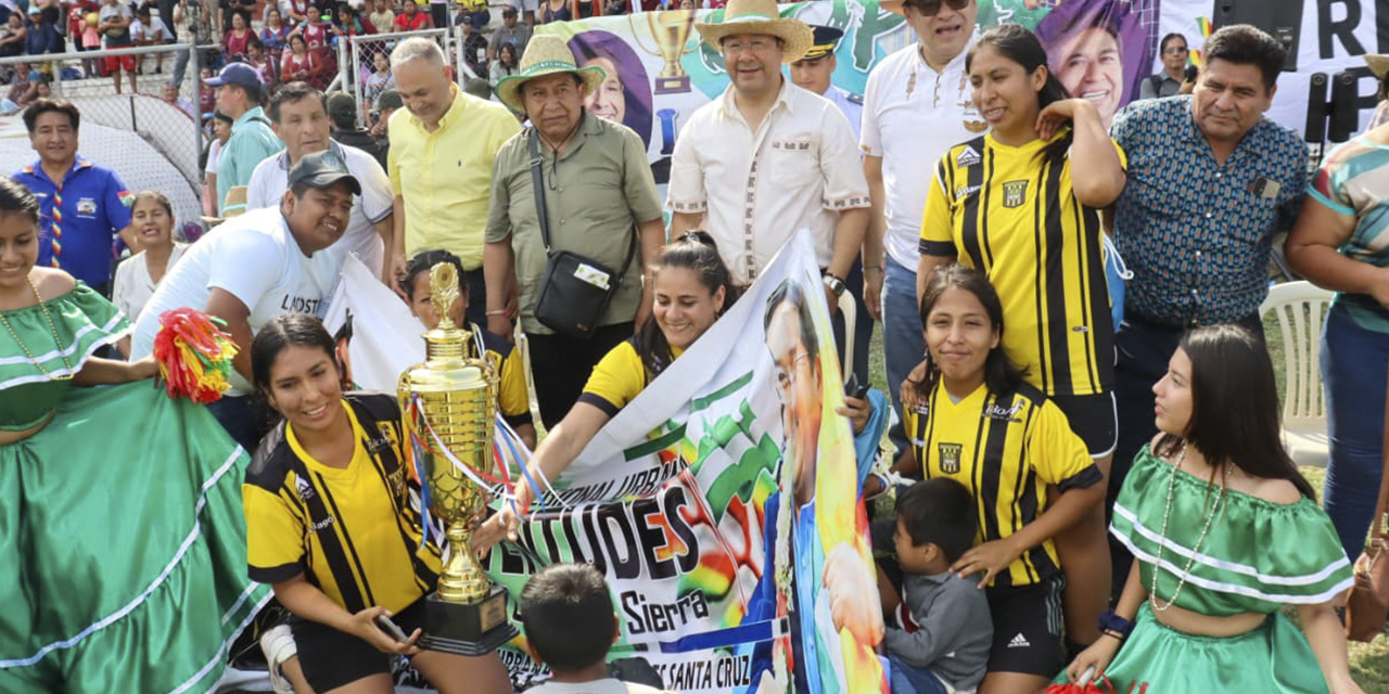 El presidente Arce y el vicepresidente Choquehuanca con las ganadoras y la copa de campeón.