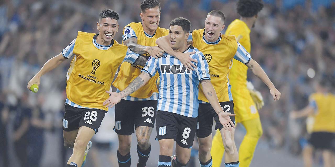 Juanfer Quintero (8) es congratulado por sus compañeros de Racing después de convertir los dos goles del triunfo.