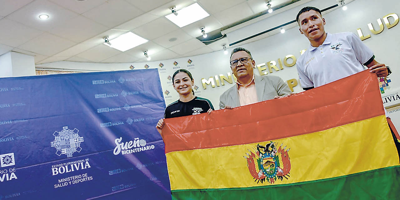 El viceministro Enríquez entrega la bandera a los deportistas Sol Sandoval y David Ninavia.