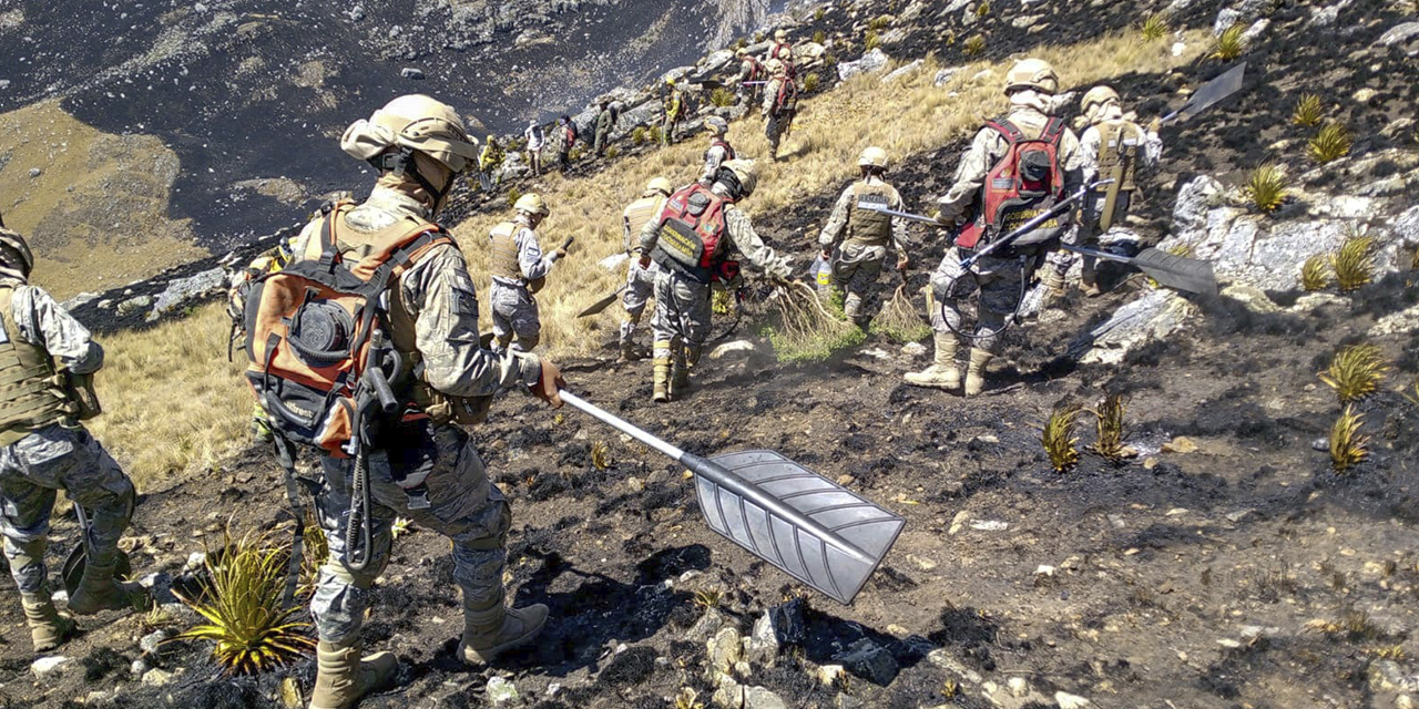 Militares en plena labor de enfriamiento del campo dañado por el fuego, en Cochabamba.