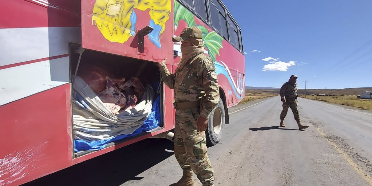 Un militar ejecuta labores de control a un bus en una carretera internacional.