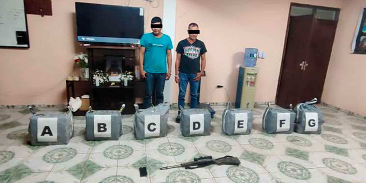 Los dos detenidos, las bolsas de yute en las que trasladaban más de 200 paquetes con cocaína, además del arma de fuego incautada. Foto: RRSS