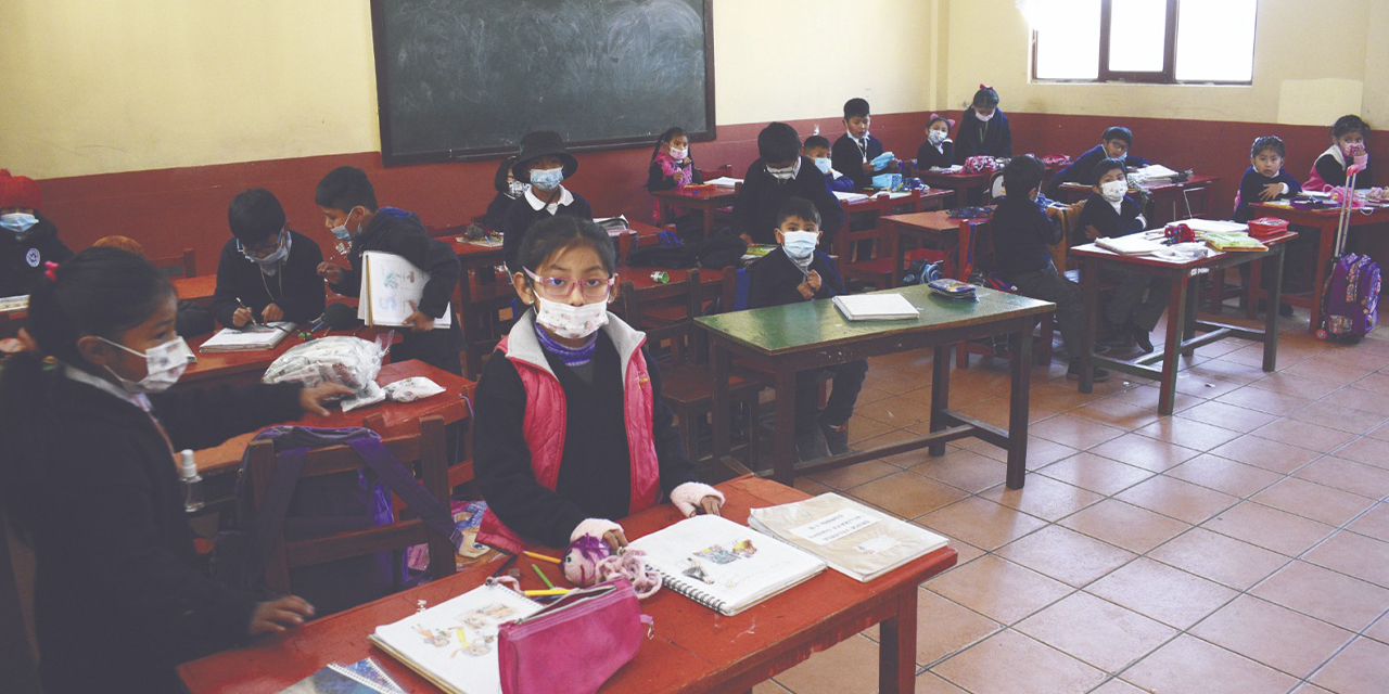 Niños y niñas esperan a su maestra dentro de su aula.