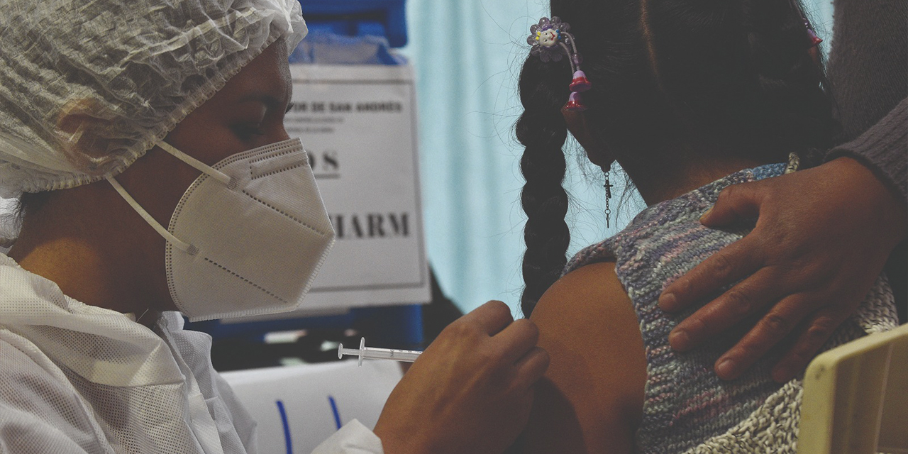 Una niña recibe una vacuna de personal de salud. 