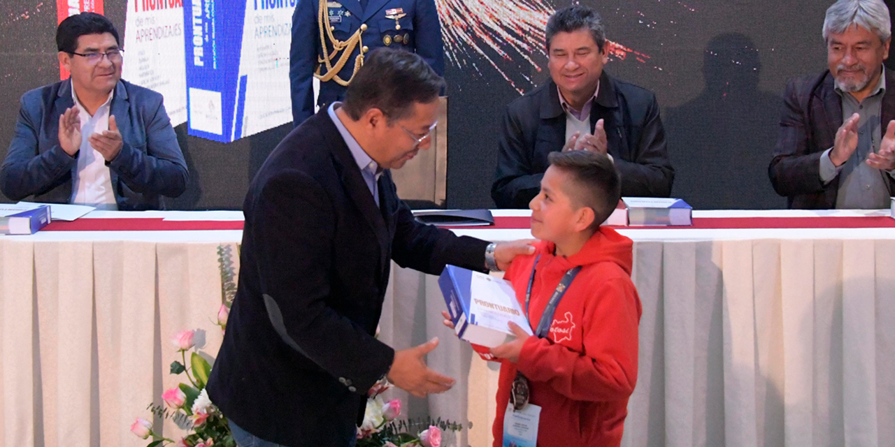 El presidente Luis Arce entrega un ejemplar del “Prontuario de mis aprendizajes” para Primaria a Tiago Alborta Dávalos. Foto: Josué Cortez