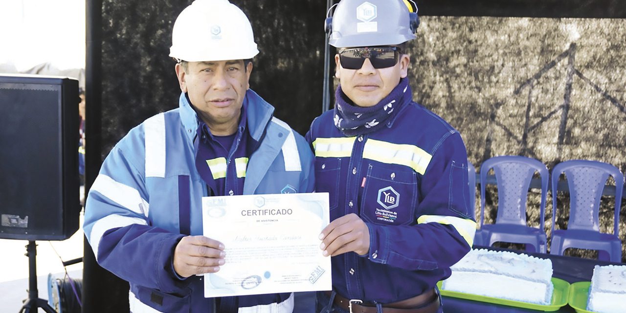 Dos de los trabajadores que recibieron certificados por su capacitación en reparación de las piscinas de evaporación.