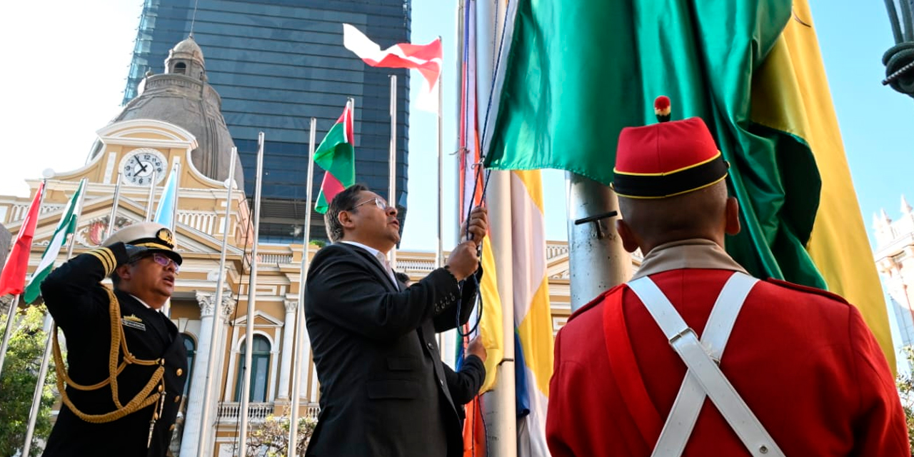 El presidente Luis Arce iza la bandera nacional durante el acto en plaza Murillo, en La Paz. Foto: Comunicación Presidencial