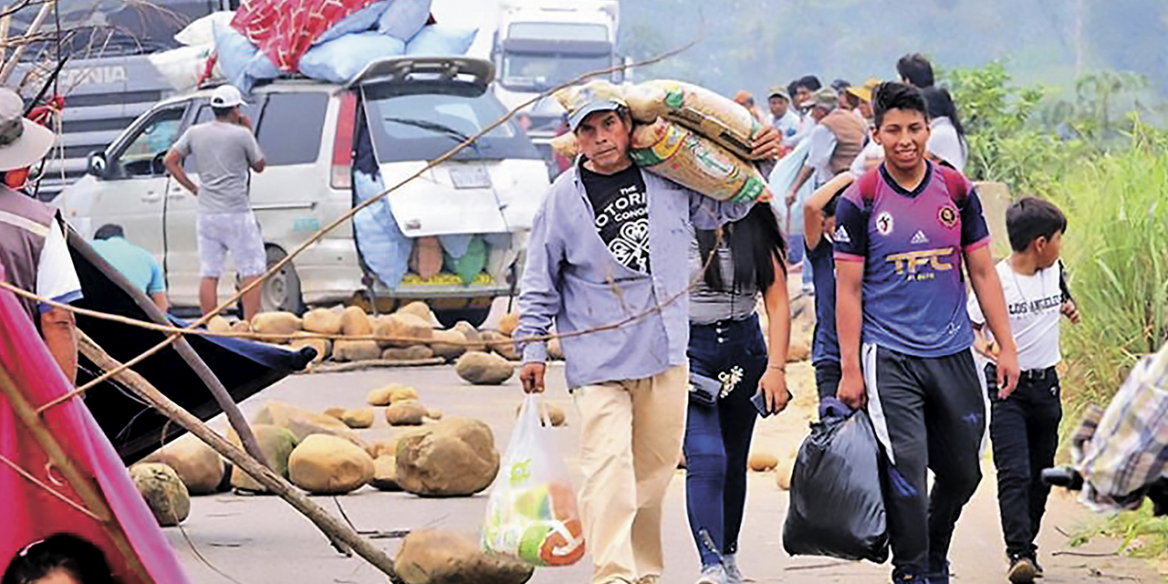 Personas caminan en un punto de bloqueo cargando alimentos. | Foto: Notibol