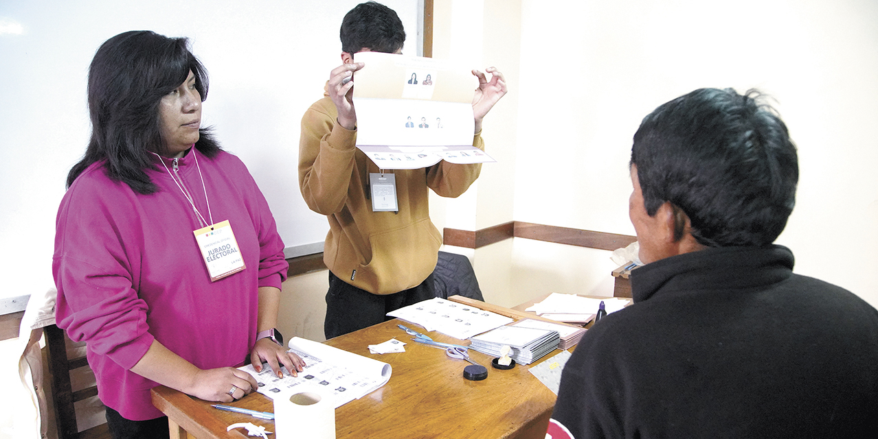 Dos jurados electorales, uno muestra la papeleta electoral de las judiciales.