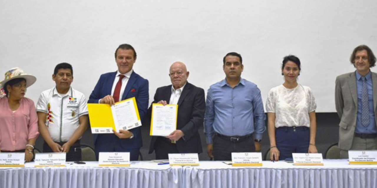 Vocales del TSE y el director ejecutivo del CEAE, Fabio Bargiacchi, muestran la firma del acuerdo.